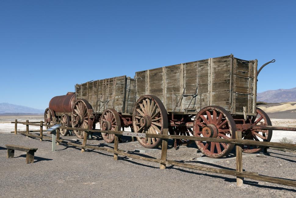 Free Image of Row of Old Wooden Wagons in a Dirt Field 