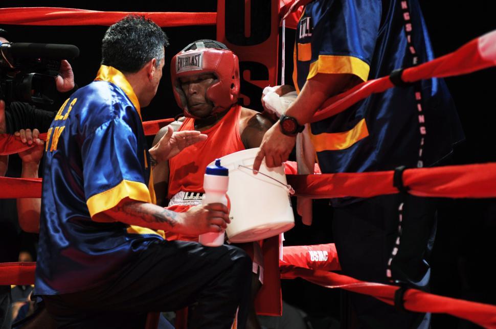 Free Image of Man in Blue and Yellow Shirt Sitting in Boxing Ring 