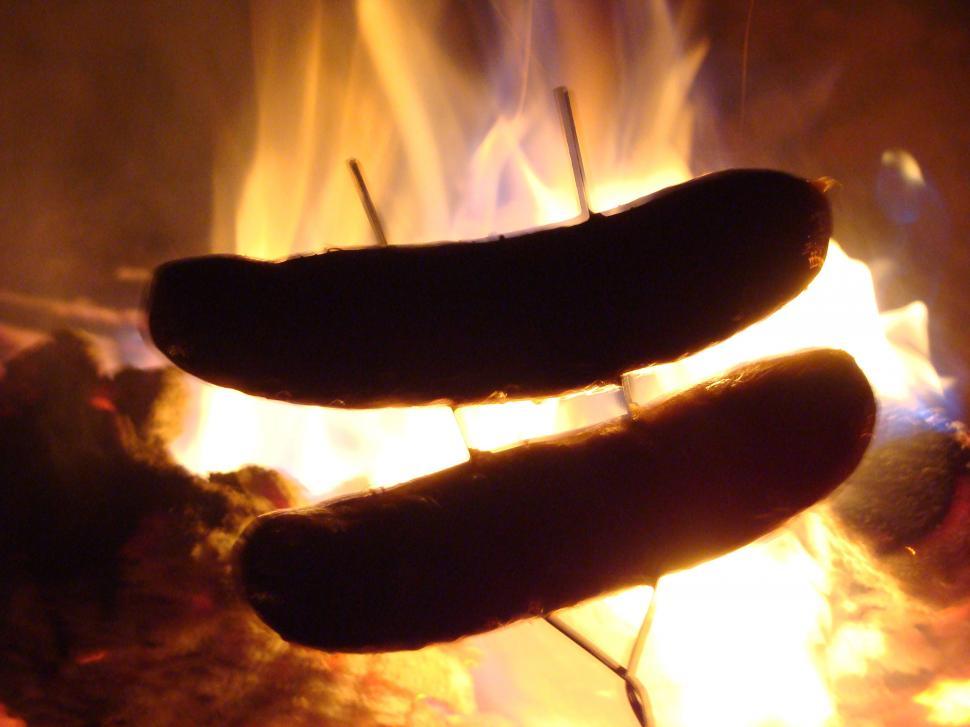 Free Image of Two Hot Dogs Roasting Over a Fire 