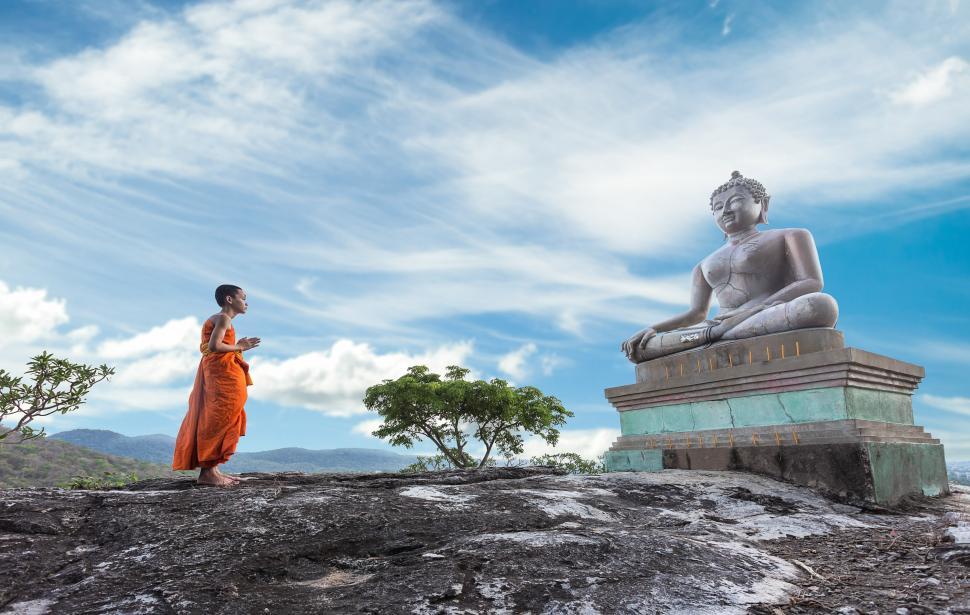 Free Image of Woman in Orange Dress Standing Next to Buddha Statue 