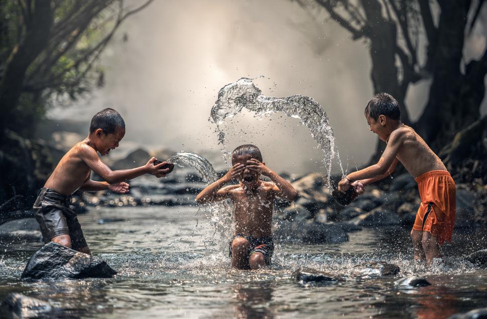 Free Image of Three Children Playing in a Stream of Water 