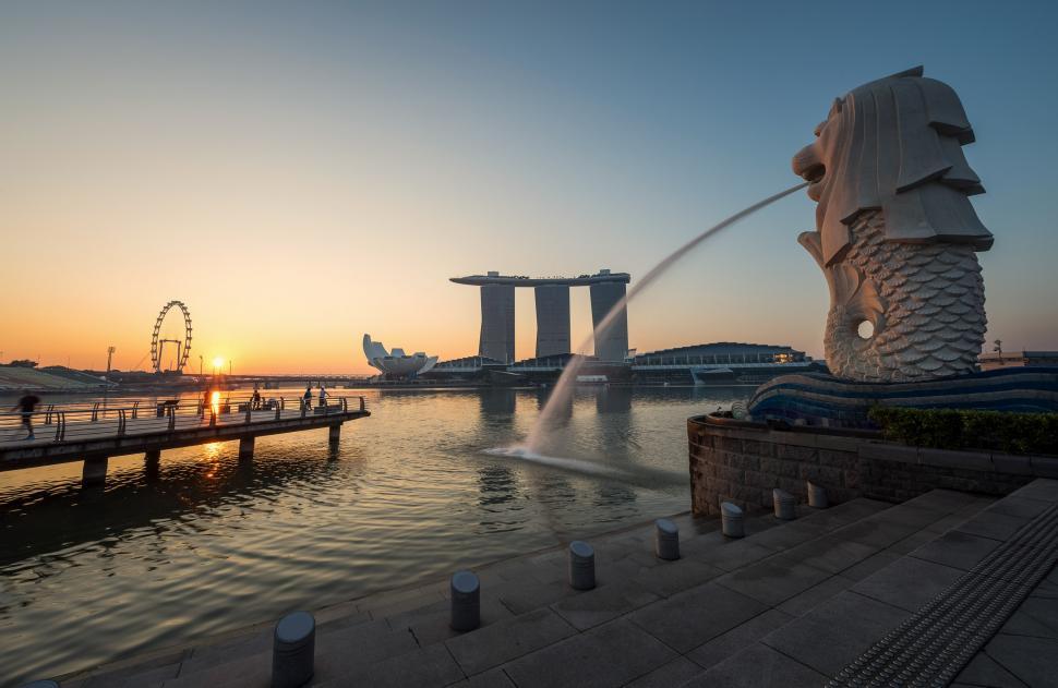 Free Image of Sun Setting Over Water With Foreground Statue 