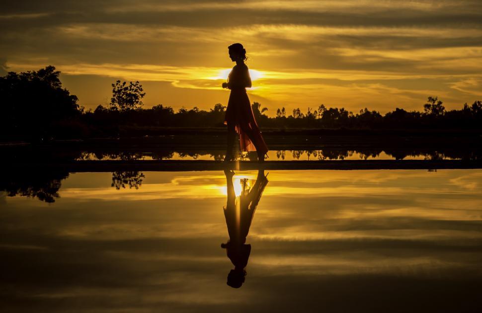 Free Image of Person Walking Across Body of Water at Sunset 