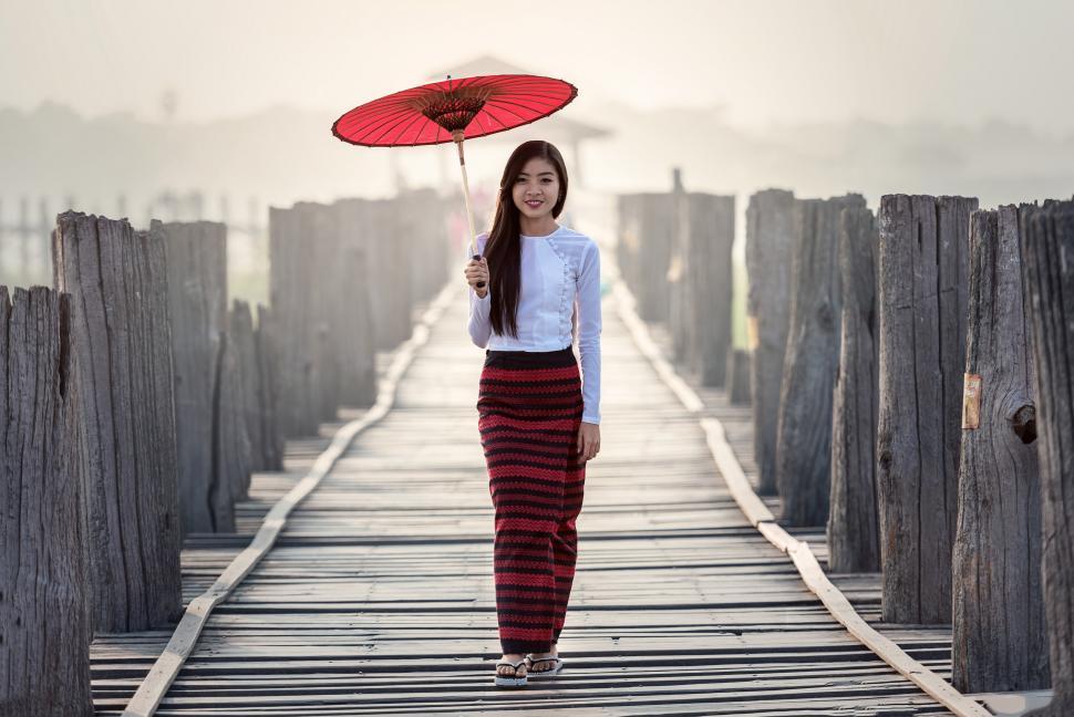Free Image of Woman Standing on Bridge Holding Umbrella 