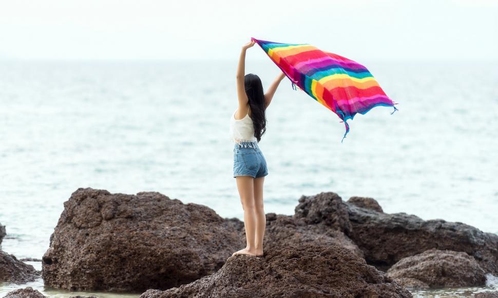 Free Image of Woman Standing on Rock Holding Colorful Kite 