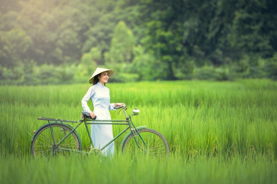 Free Image of Woman Standing in Field With Bicycle 