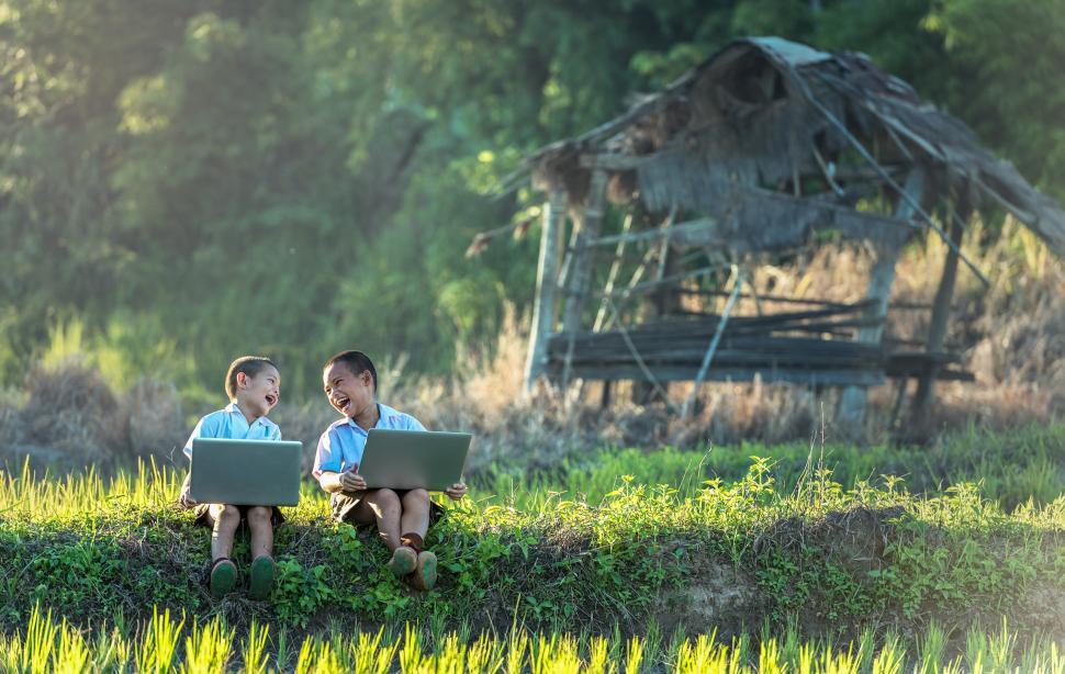 Free Image of Two Young Boys Sitting on Grass Using Laptops 