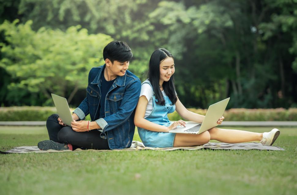 Free Image of Man and Woman Sitting on Grass With Laptops 