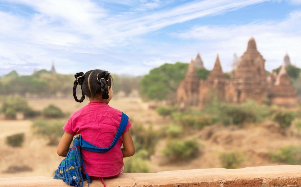 Free Image of Little Girl Sitting on Ledge, Looking at Landscape 