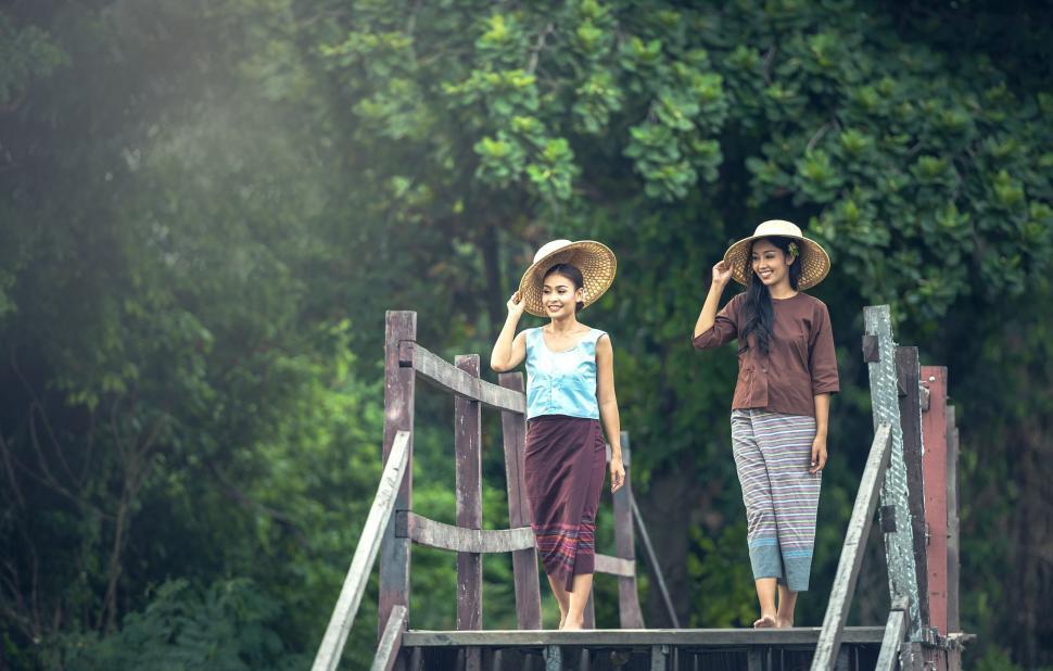 Free Image of Two Women Standing on Top of a Wooden Bridge 
