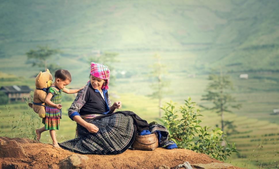 Free Image of Woman Sitting on Top of Hill With Child 