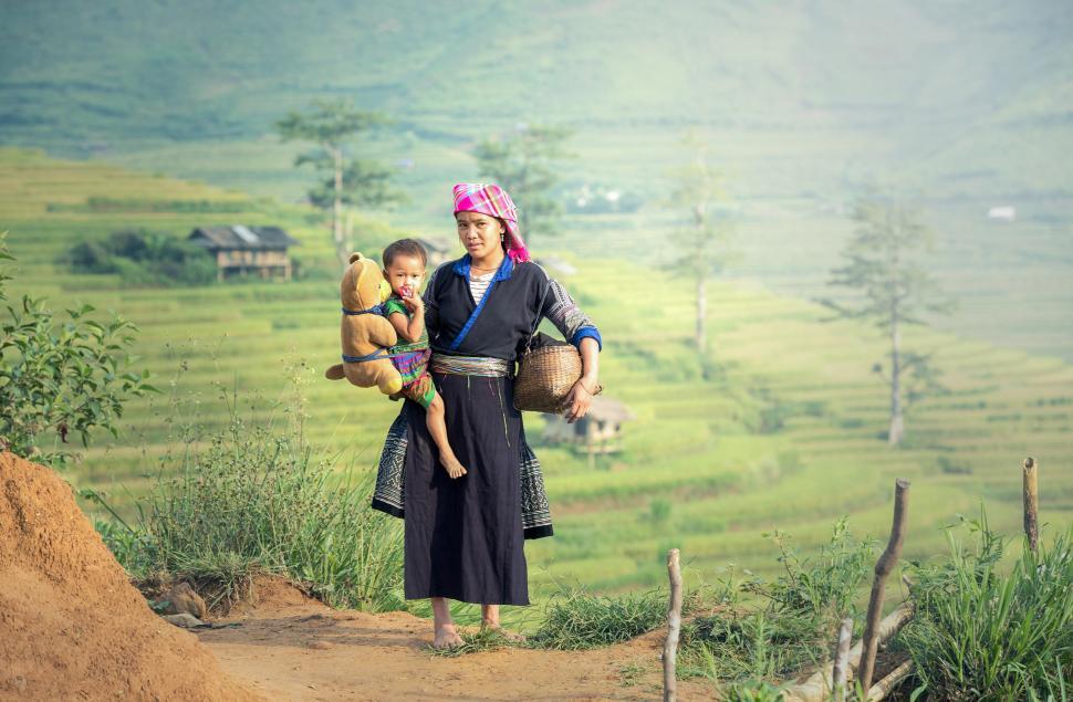 Free Image of Woman Carrying Two Children on Her Back 