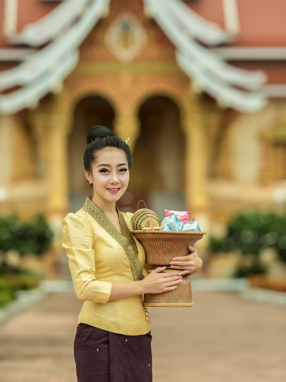 Free Image of Woman Holding a Basket of Presents in Front of a Building 