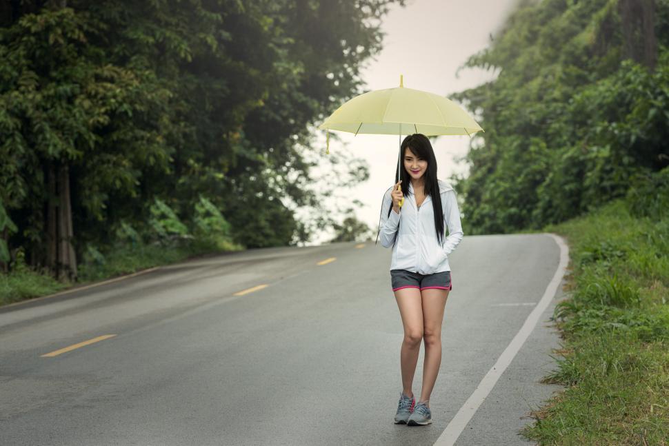 Free Image of Woman Walking Down Road Holding Umbrella 