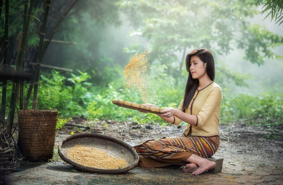 Free Image of Woman Sitting on Ground With Pan of Food 
