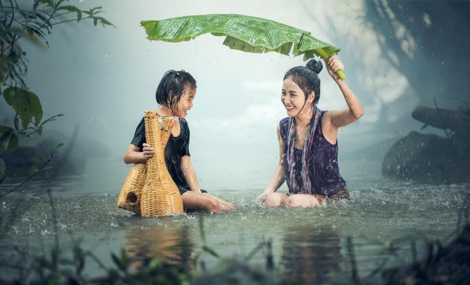Free Image of Two Women Sitting in a Body of Water Under an Umbrella 