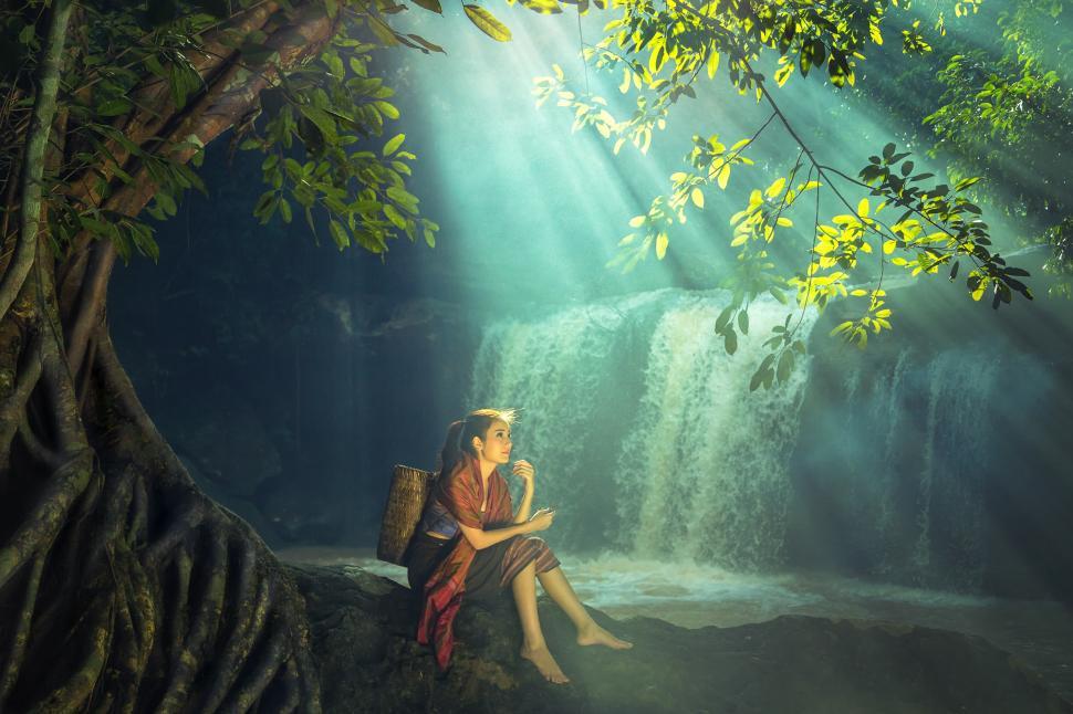 Free Image of Woman Sitting in Front of a Waterfall 