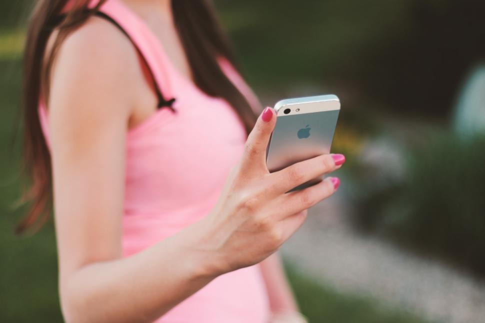 Free Image of Woman in Pink Dress Looking at Cell Phone 