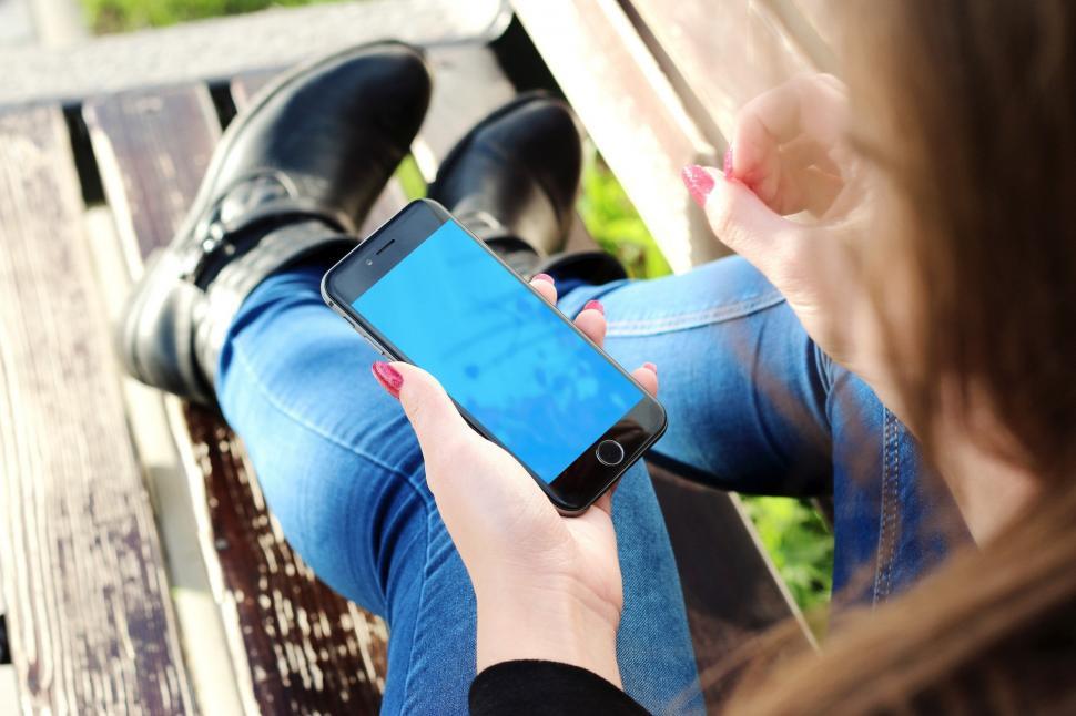 Free Image of Woman Sitting on a Bench Holding a Smart Phone 