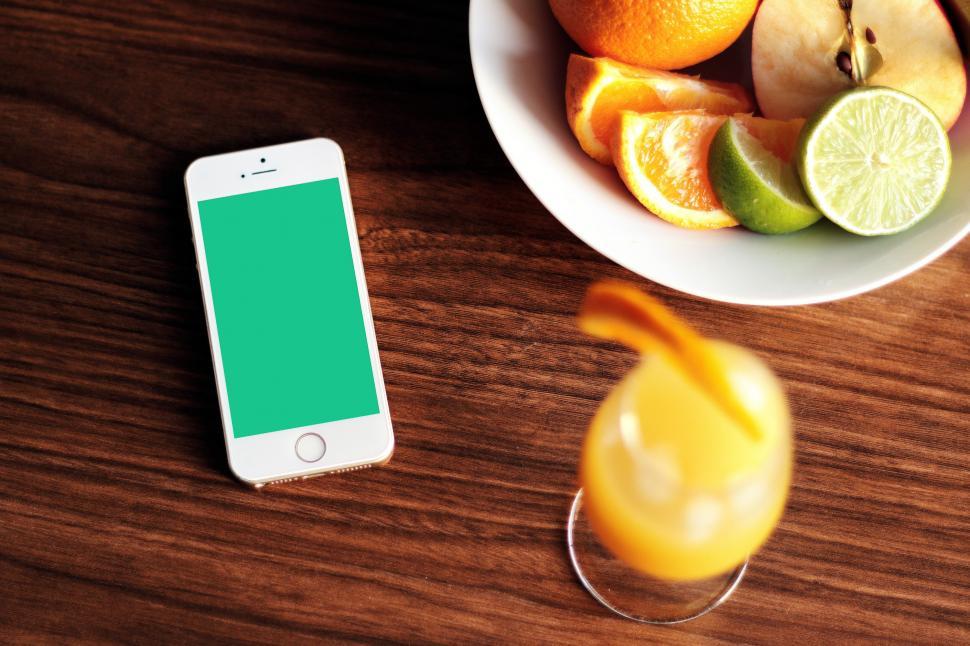 Free Image of Bowl of Oranges, Limes, and Cell Phone on Table 