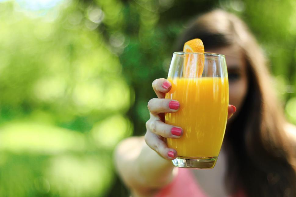 Free Image of Woman Holding a Glass of Orange Juice 
