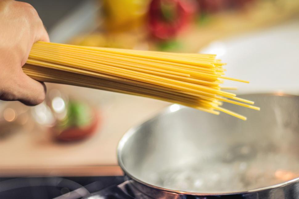 Free Image of Person Holding Bunch of Spaghetti Over Stove 
