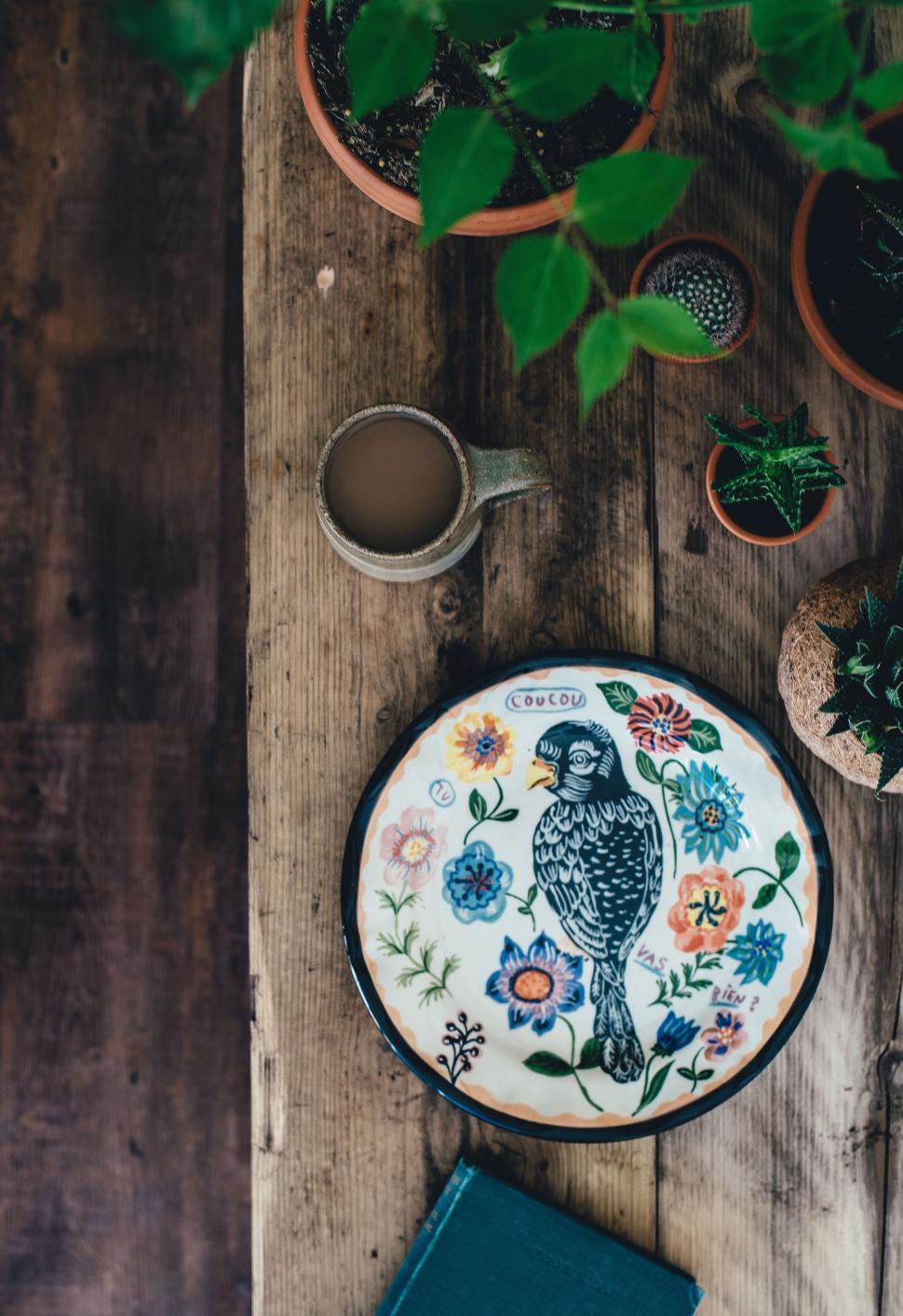Free Image of Bird Painted Plate Next to Potted Plant 