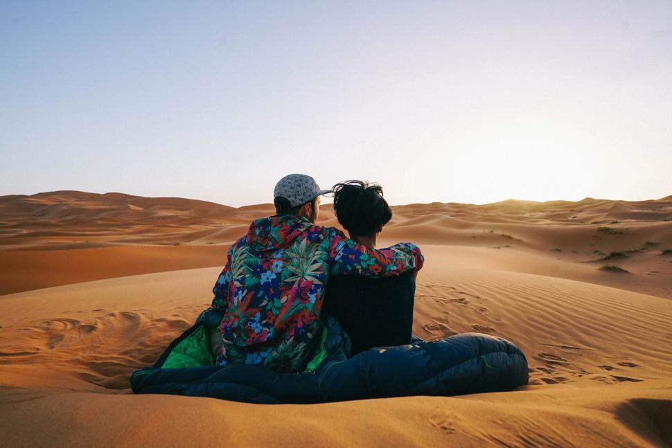Free Image of Two People Sitting in the Sand in the Desert 