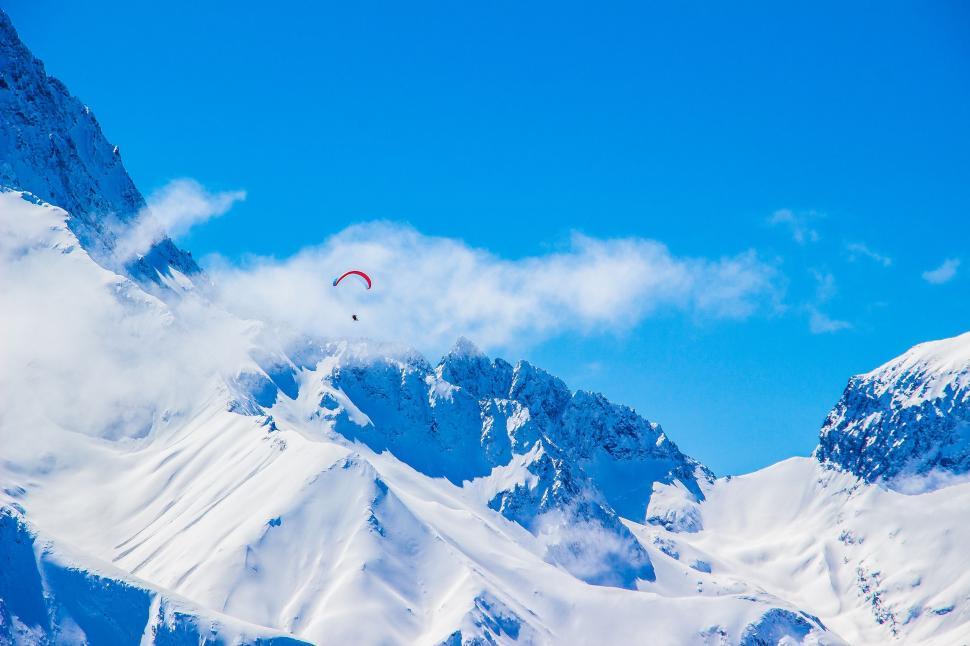 Free Image of Paraglider Soaring Above Snowy Mountain Range 