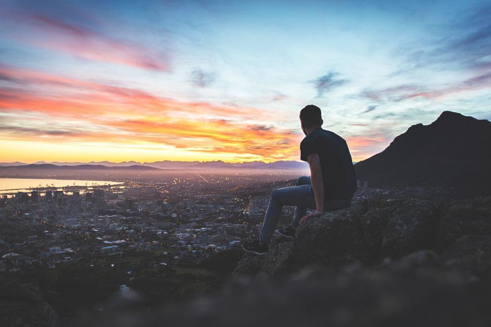 Free Image of Man Sitting on Hill Overlooking City 