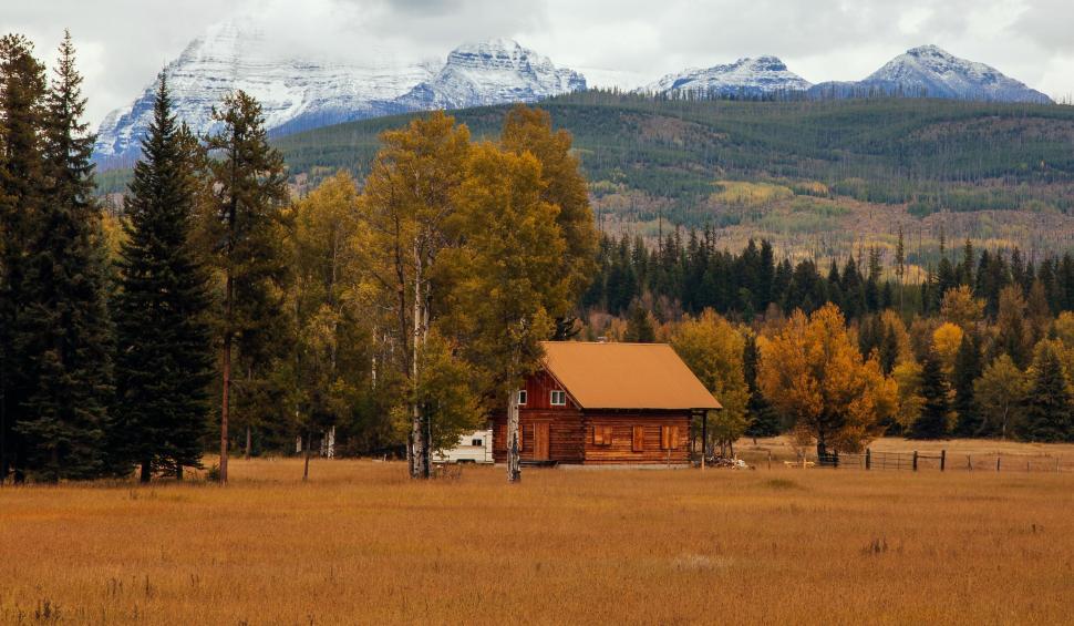 Free Image of Cabin in Field With Mountains in Background 