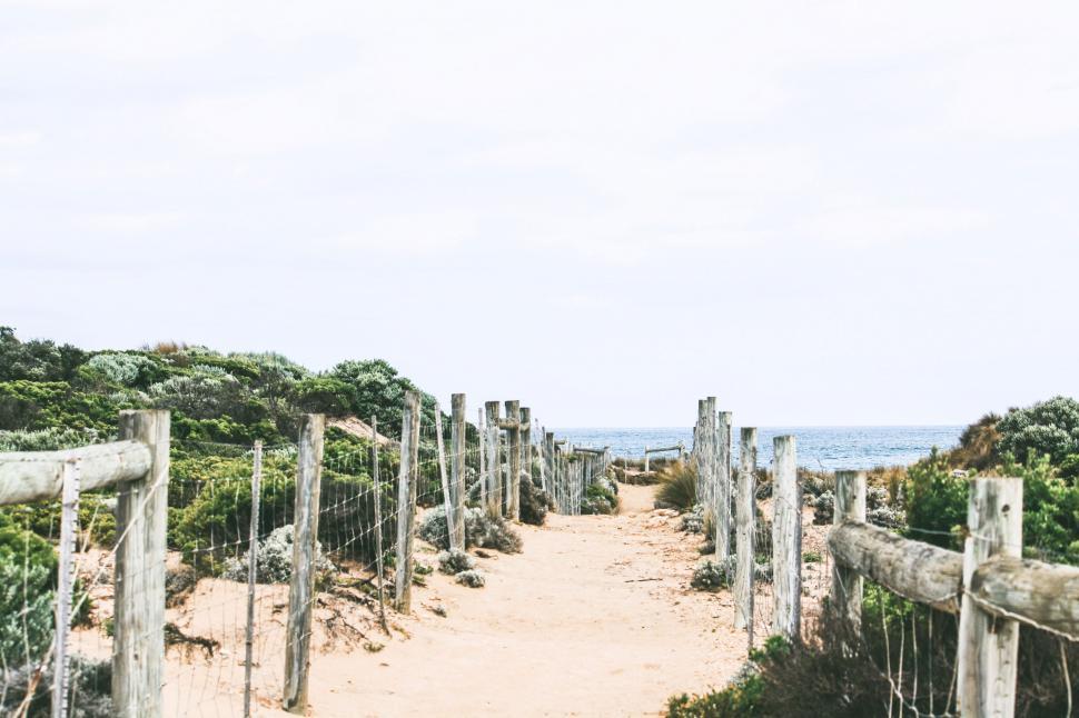 Free Image of Dirt Path Leading to Beach With Fence in Foreground 