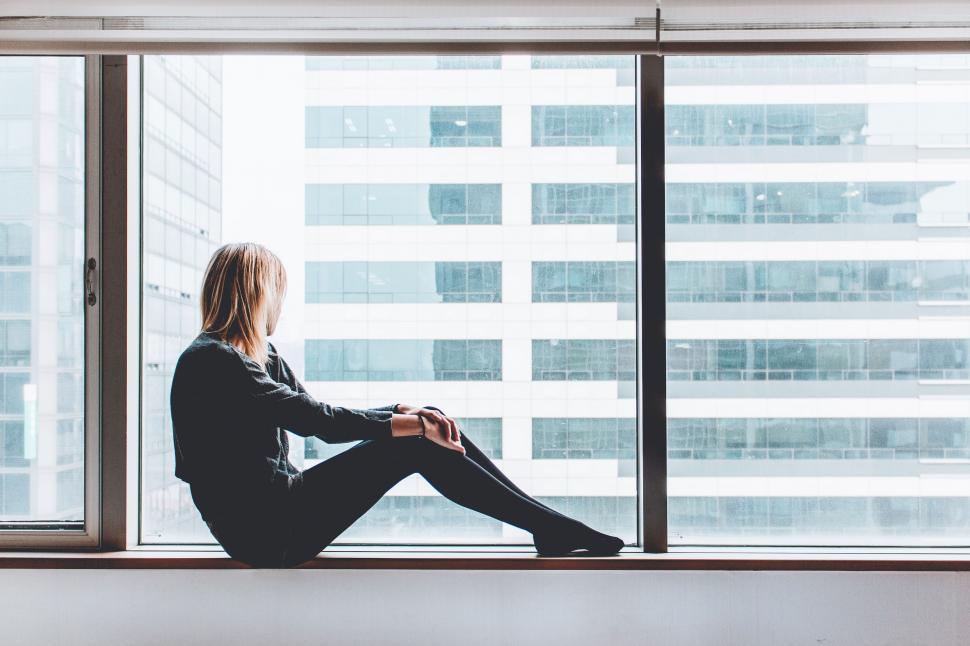 Free Image of Woman Sitting on Window Sill Looking Out 