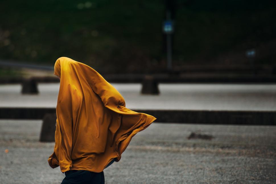 Free Image of Woman in Yellow Shawl Walking Down Street 