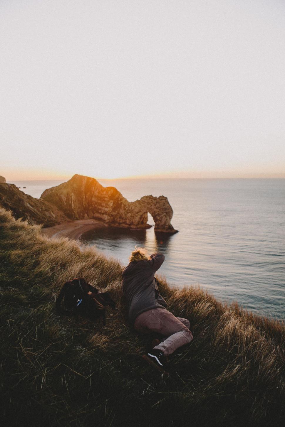 Free Image of Person Laying on Cliff Next to Ocean 