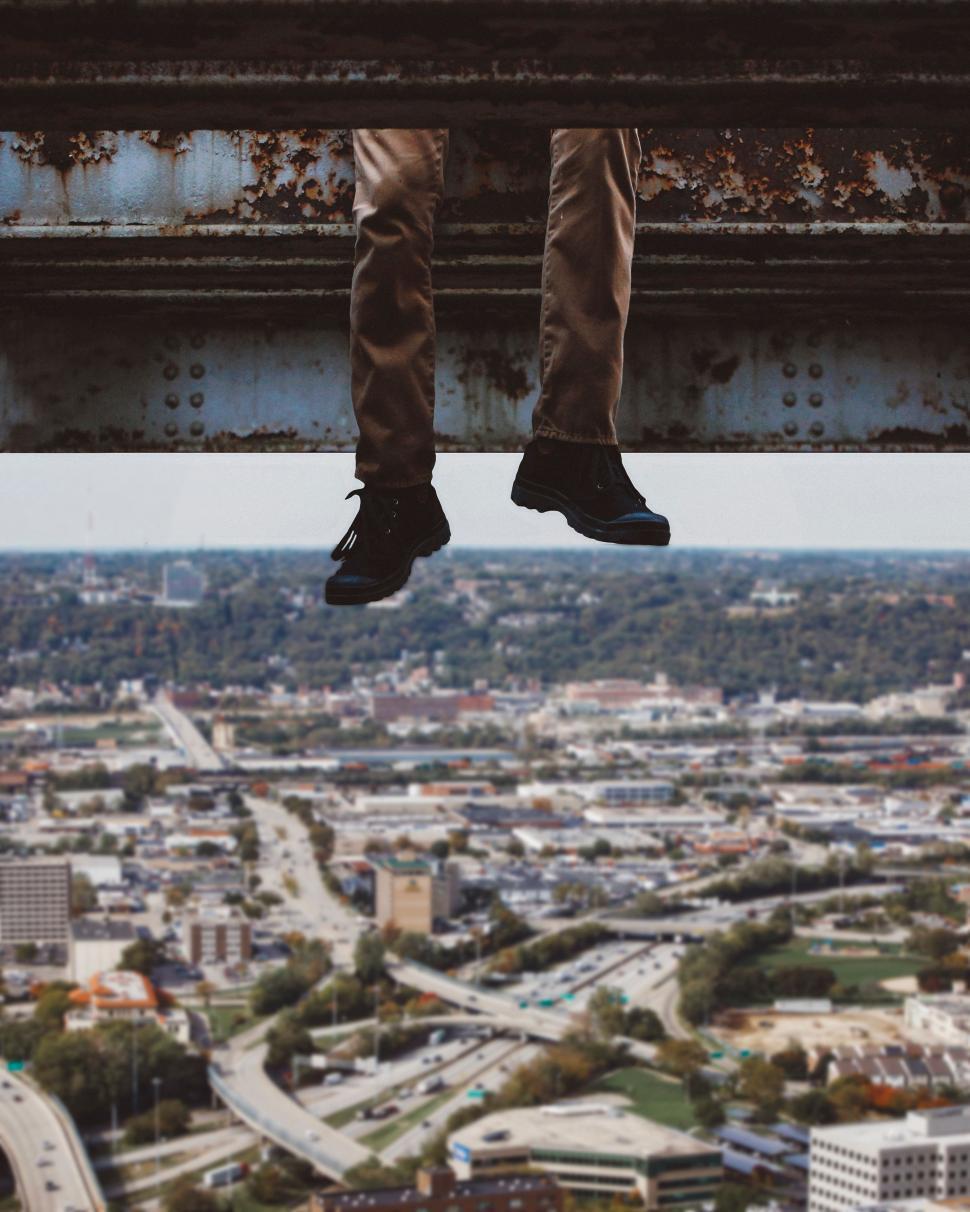 Free Image of Person Sitting on Ledge Above City 