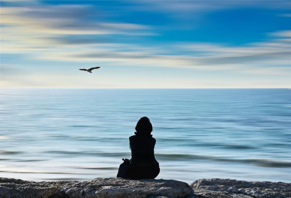 Free Image of Person Sitting on Rock Looking Out at Ocean 