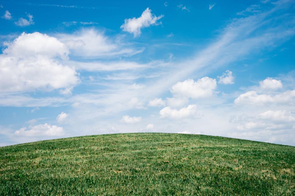 Free Image of Grass Covered Hill Under Blue Sky With Clouds 