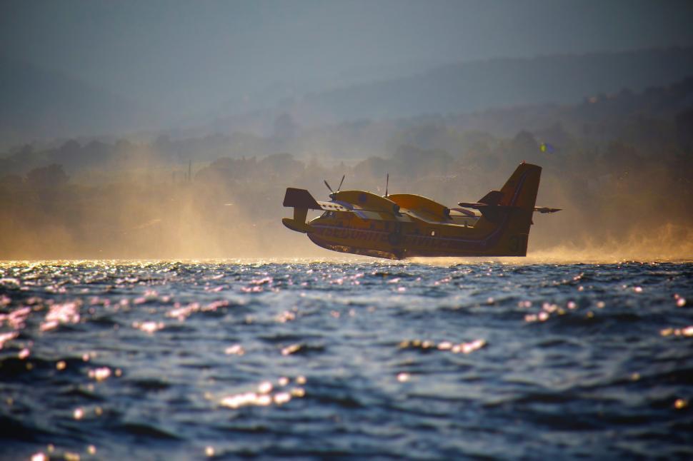 Free Image of Small Plane Flying Over Large Body of Water 