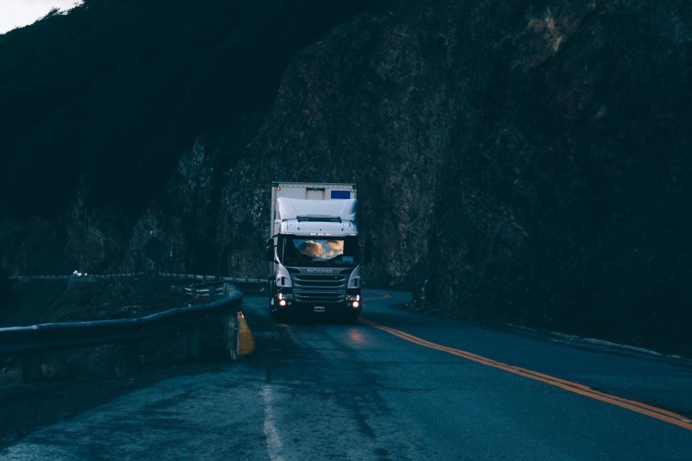 Free Image of White Truck Driving Down Road Next to Mountain 