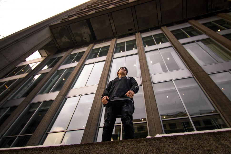 Free Image of Man Standing on Ledge in Front of Tall Building 