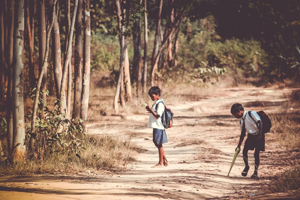 Free Image of Two Kids Walking Along a Dirt Road 