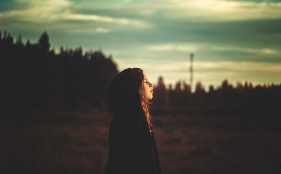 Free Image of Woman Standing in Field With Trees in Background 