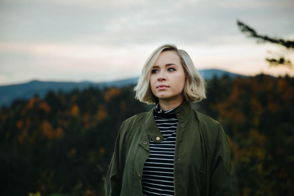 Free Image of Woman With Blonde Hair Standing in Front of a Mountain 