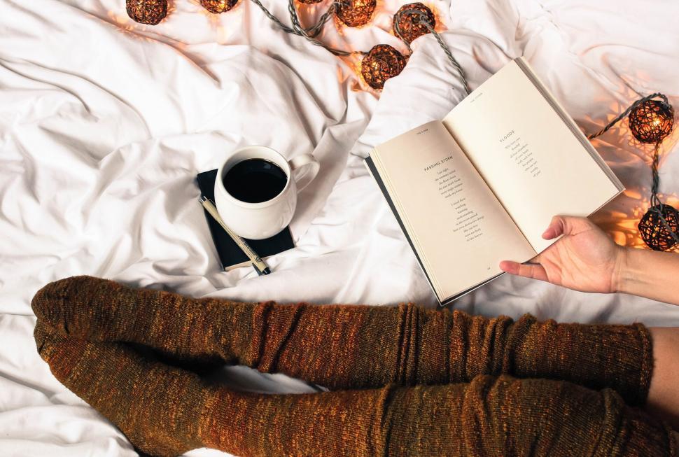 Free Image of Person Reading Book and Drinking Coffee on Bed 