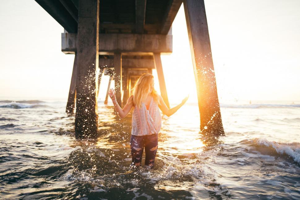 Free Image of Woman Standing in Water Under Pier 