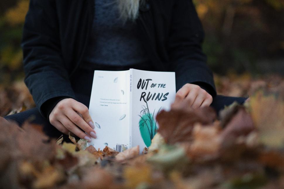 Free Image of Person Sitting in Pile of Leaves Reading a Book 