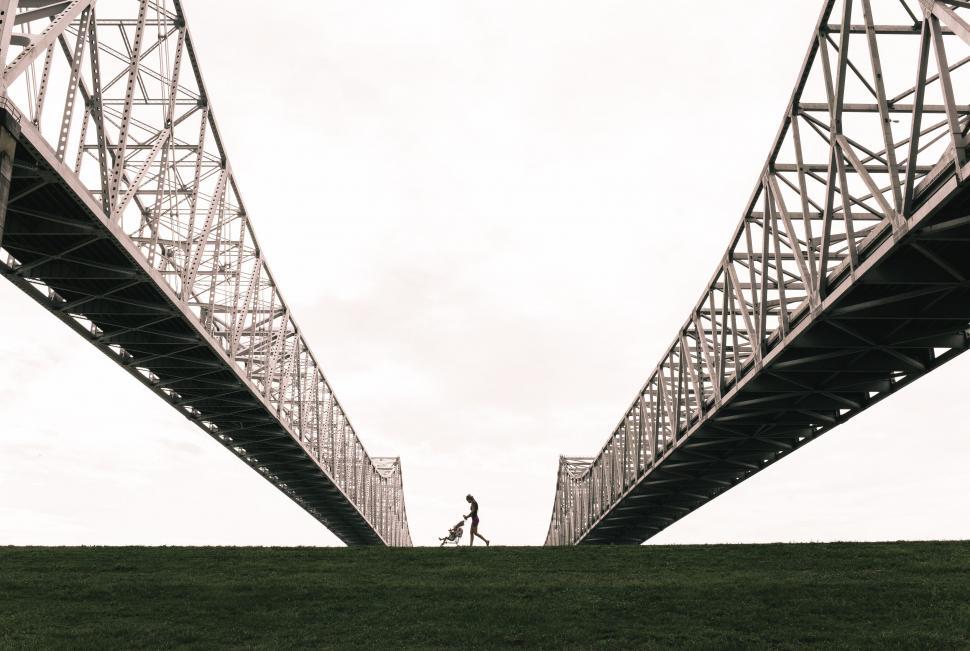 Free Image of Person Walking Across Bridge Over Lush Green Field 
