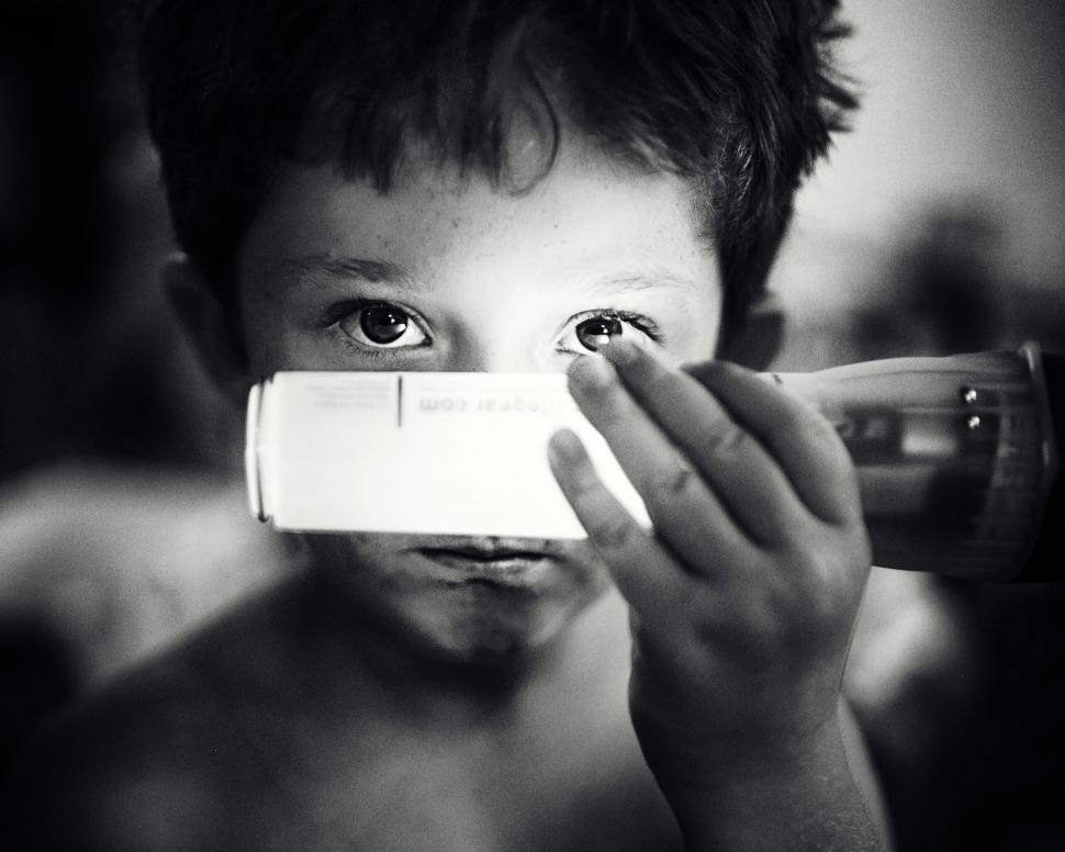 Free Image of Young Boy Looking Through a Camera Lens 