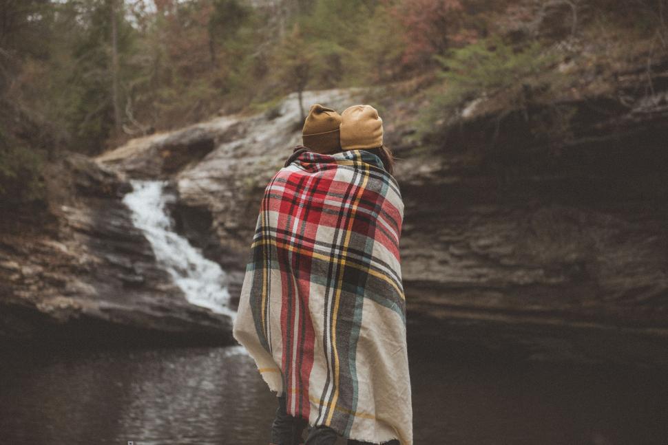 Free Image of Person Wrapped in Blanket Standing in Front of Waterfall 
